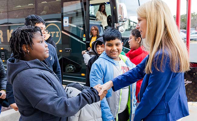Blonde NWFCU Foundation volunteer mentor shaking hands with student
